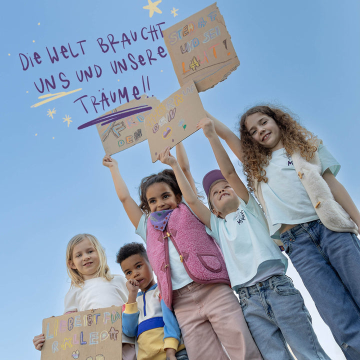 Kinder halten Transparente in die Luft. Schriftzug: "Die Welt braucht unsere Träume!"